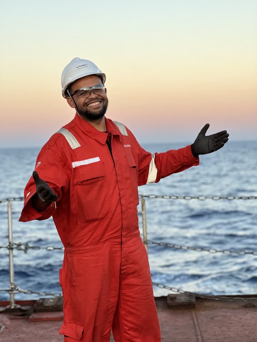Matheus Rangel embarcado, de macacão, no convés de um navio